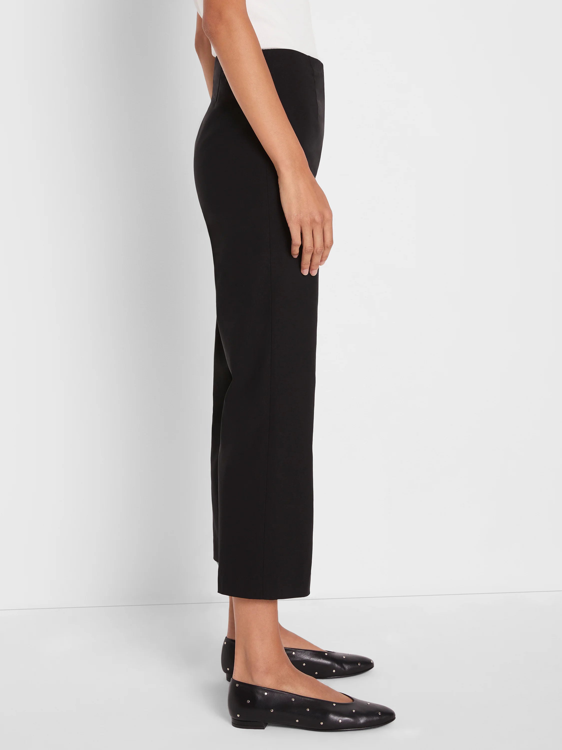 Black, smooth wide-leg crop pants shown on a model in side profile, ending above the ankle.