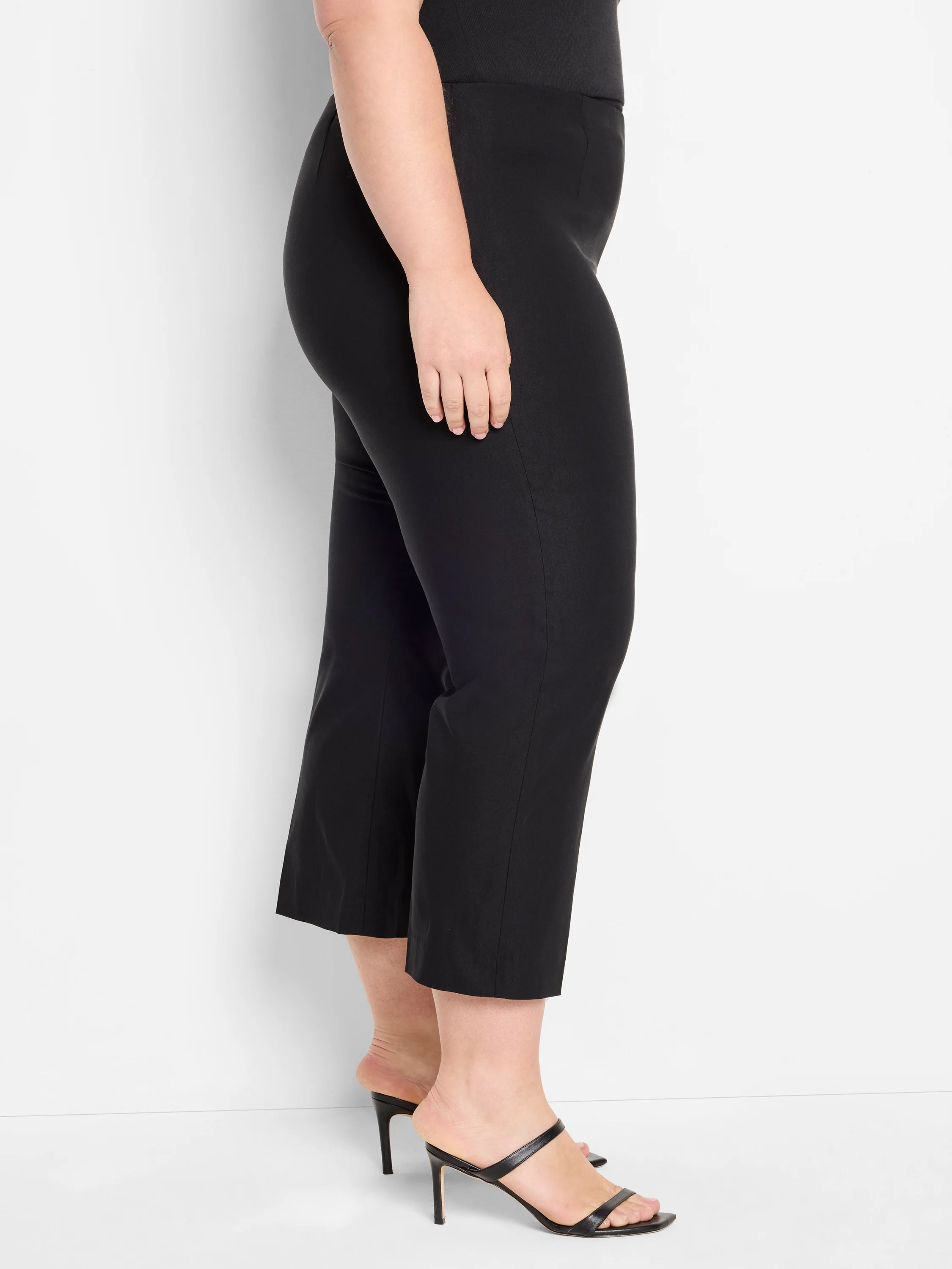 Black wide-leg crop pants on a model, side view. Smooth fabric, ends above ankles.