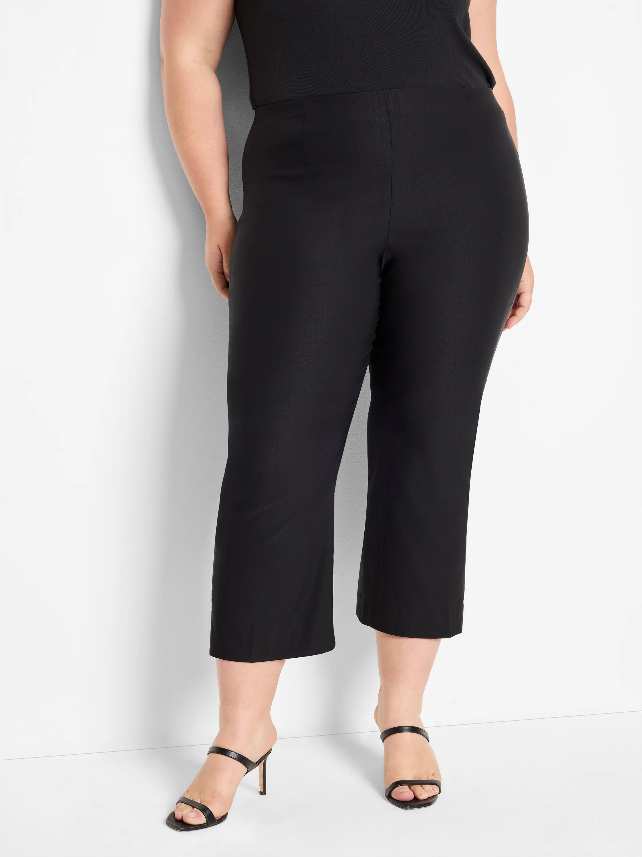 Black polished wide-leg crop pants, shown on a model. Pants end at mid-calf.