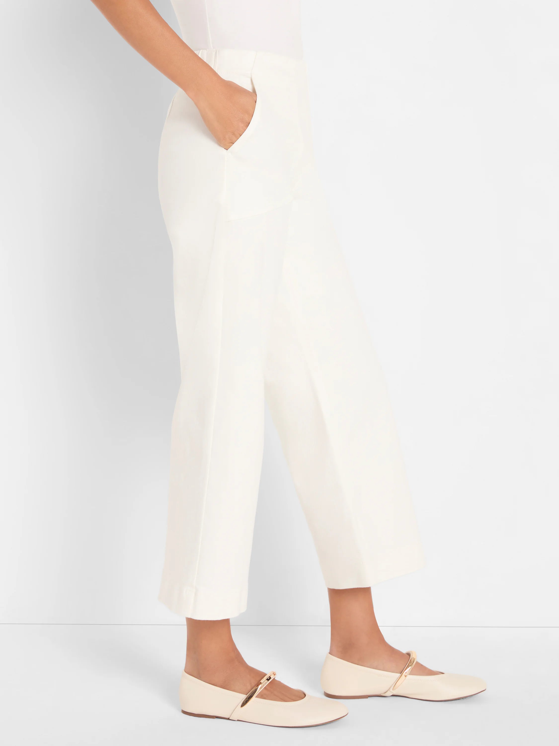 Cream, wide-leg, cropped pants with a hand in the pocket.
