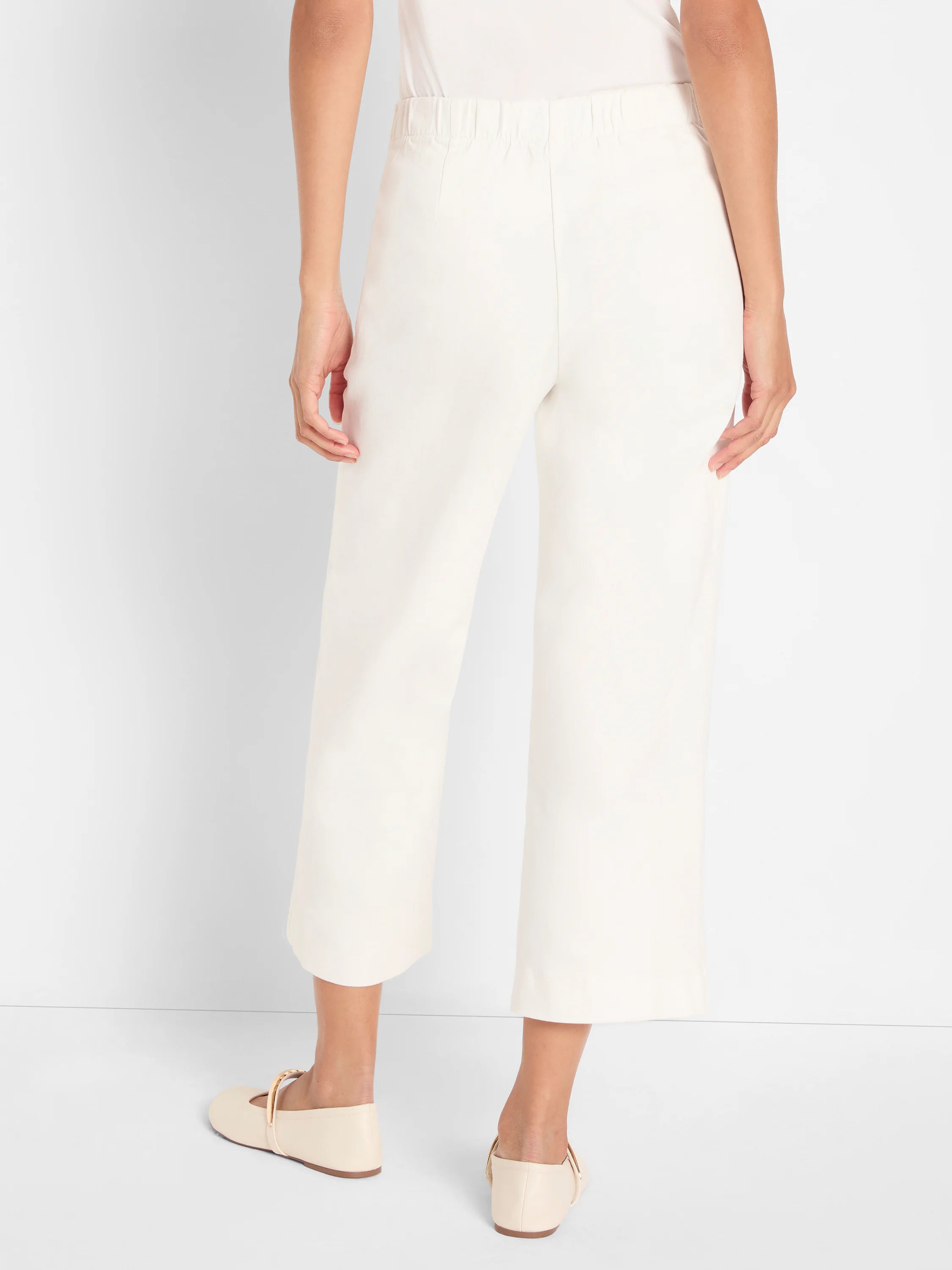 Cream wide-leg cropped jeans on a model from behind, showing an elasticated waist.