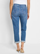 Medium blue girlfriend jeans, shown from the back, with cuffed ankles and decorative M-shaped stitching on the back pockets.