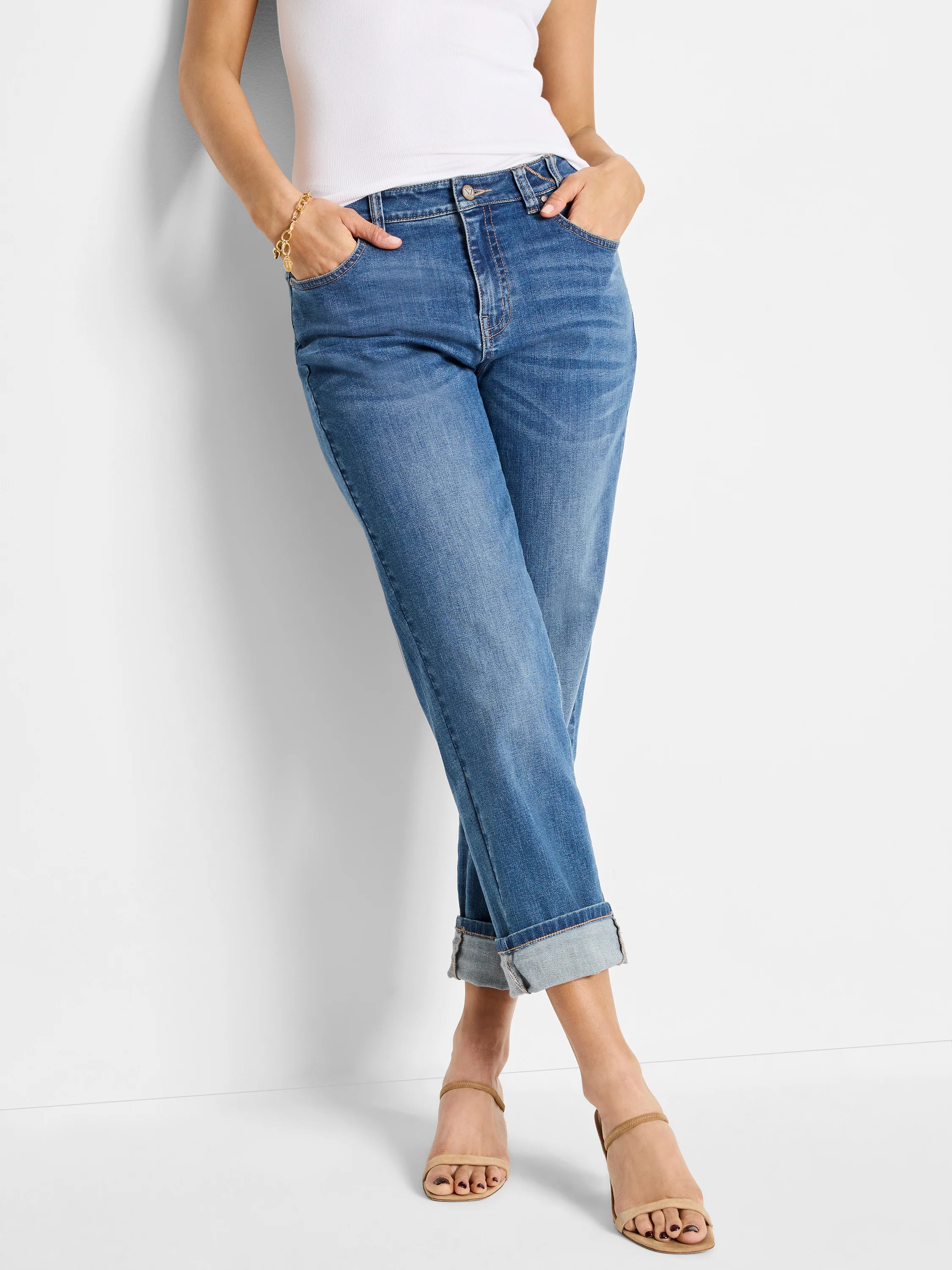 Medium blue wash girlfriend jeans with faded thighs and cuffed ankles.