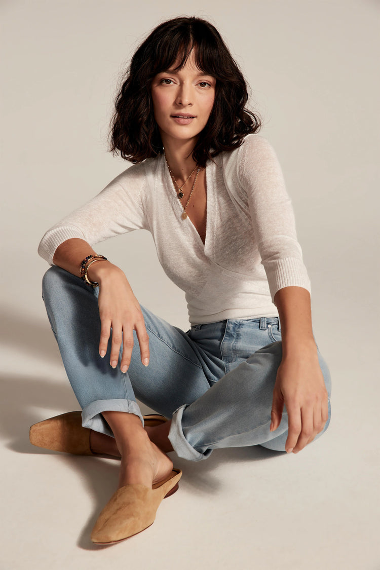 Light blue wash girlfriend jeans, mid-rise, cuffed at ankles. Model wears them sitting cross-legged.