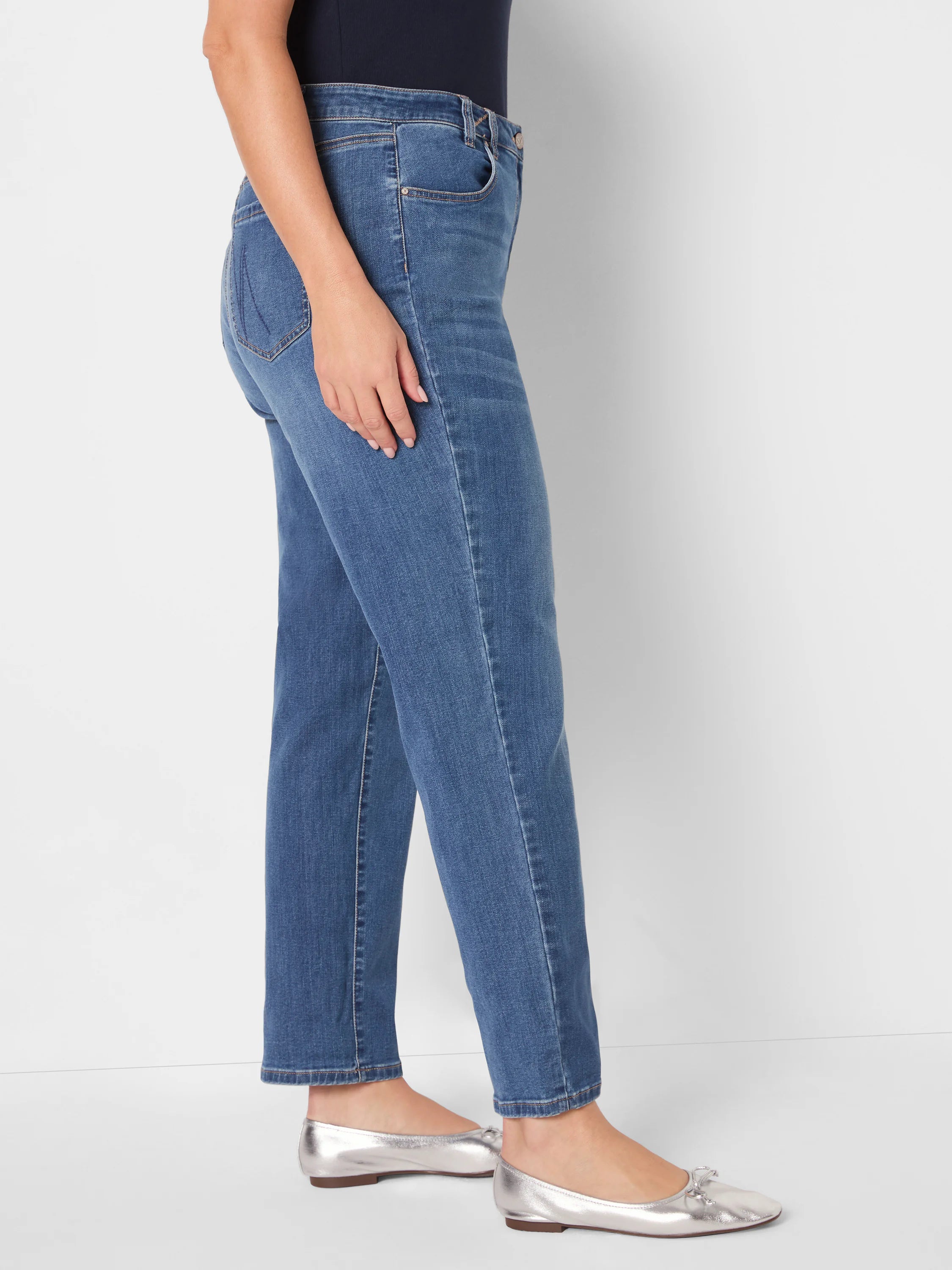 Medium blue mid-rise girlfriend jeans, relaxed fit with subtle fading and tan contrast stitching.