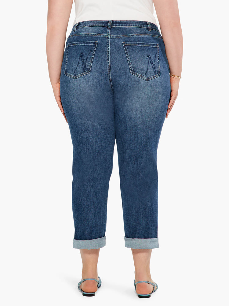 Medium blue mid-rise girlfriend jeans, back view. Faded denim, stitched back pockets, rolled cuffs show lighter interior.