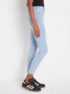 Light blue, mid-rise slim ankle jeans with subtle whiskering on thighs and metal rivets on front pockets.