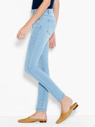 Model wears light wash, high-rise skinny jeans that fit closely and stop above the ankle.