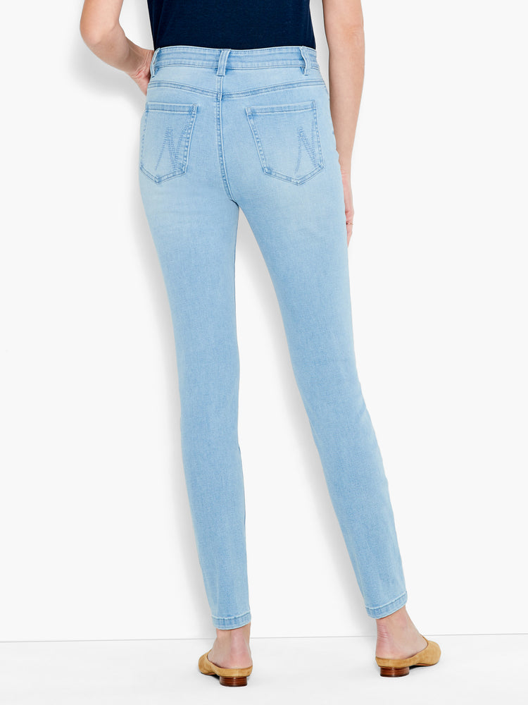 Light wash slim-fit denim jeans are shown from the back, featuring stitched arcuate back pockets.