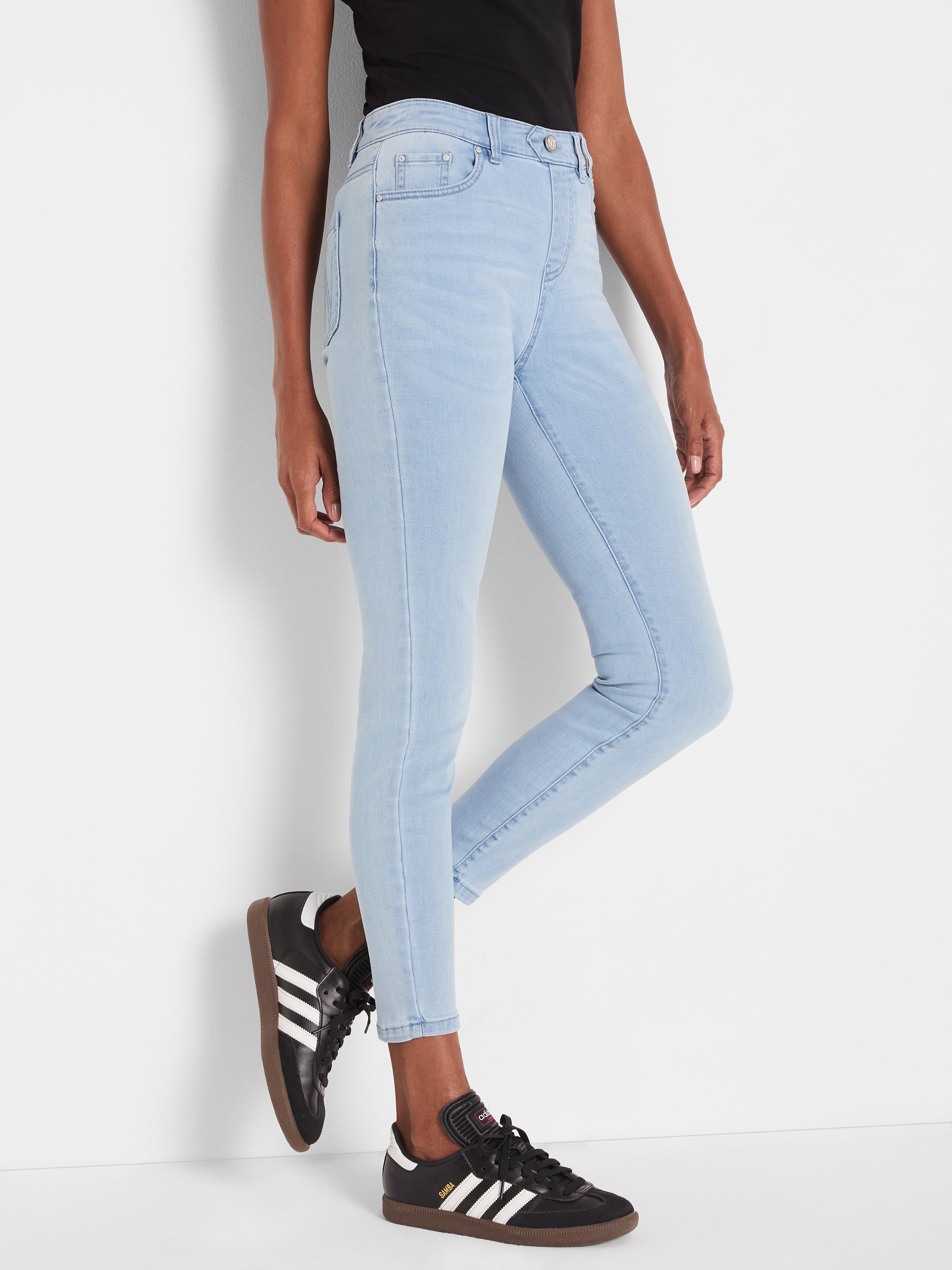 The model wears snug, cropped, light wash high-rise skinny jeans with classic five-pocket detailing.