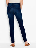 Deep indigo slim fit jeans are worn by the model, featuring a dark wash and classic rear patch pockets.