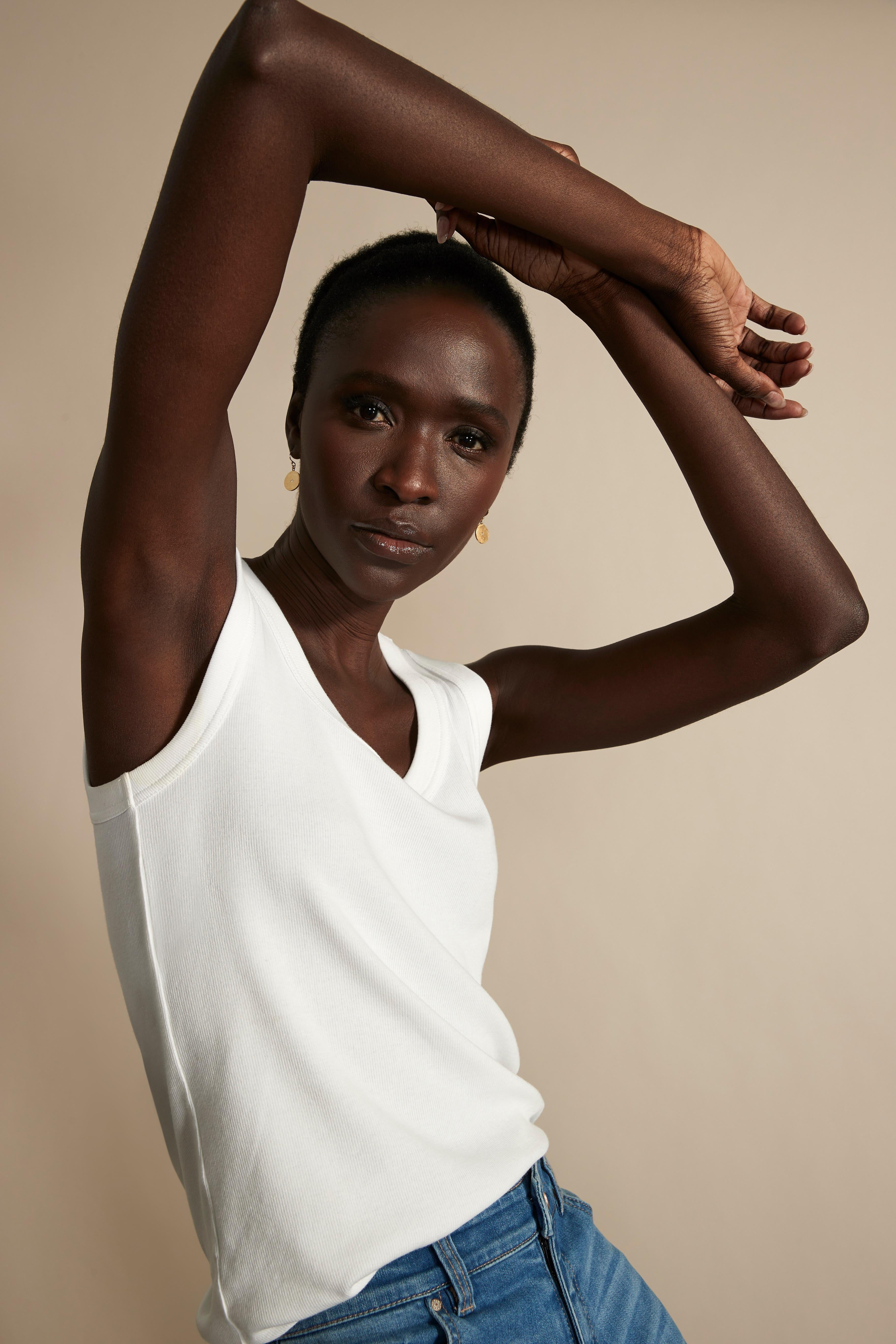 A fitted white ribbed tank top with a V-neck is shown on the model.
