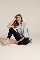 Dark indigo slim ankle jeans on a seated model. The denim has a deep, uniform blue wash and a fitted silhouette.