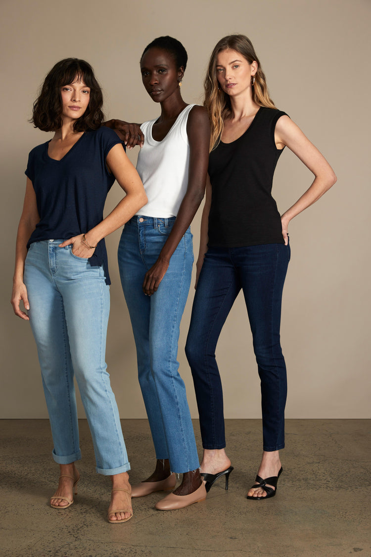 Models wear three distinct styles of women's blue jeans: light wash cuffed, medium-dark straight, and dark skinny.