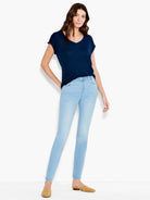 Light blue slim-cut ankle jeans on a model.  The model also wears a dark navy v-neck t-shirt and light brown shoes.