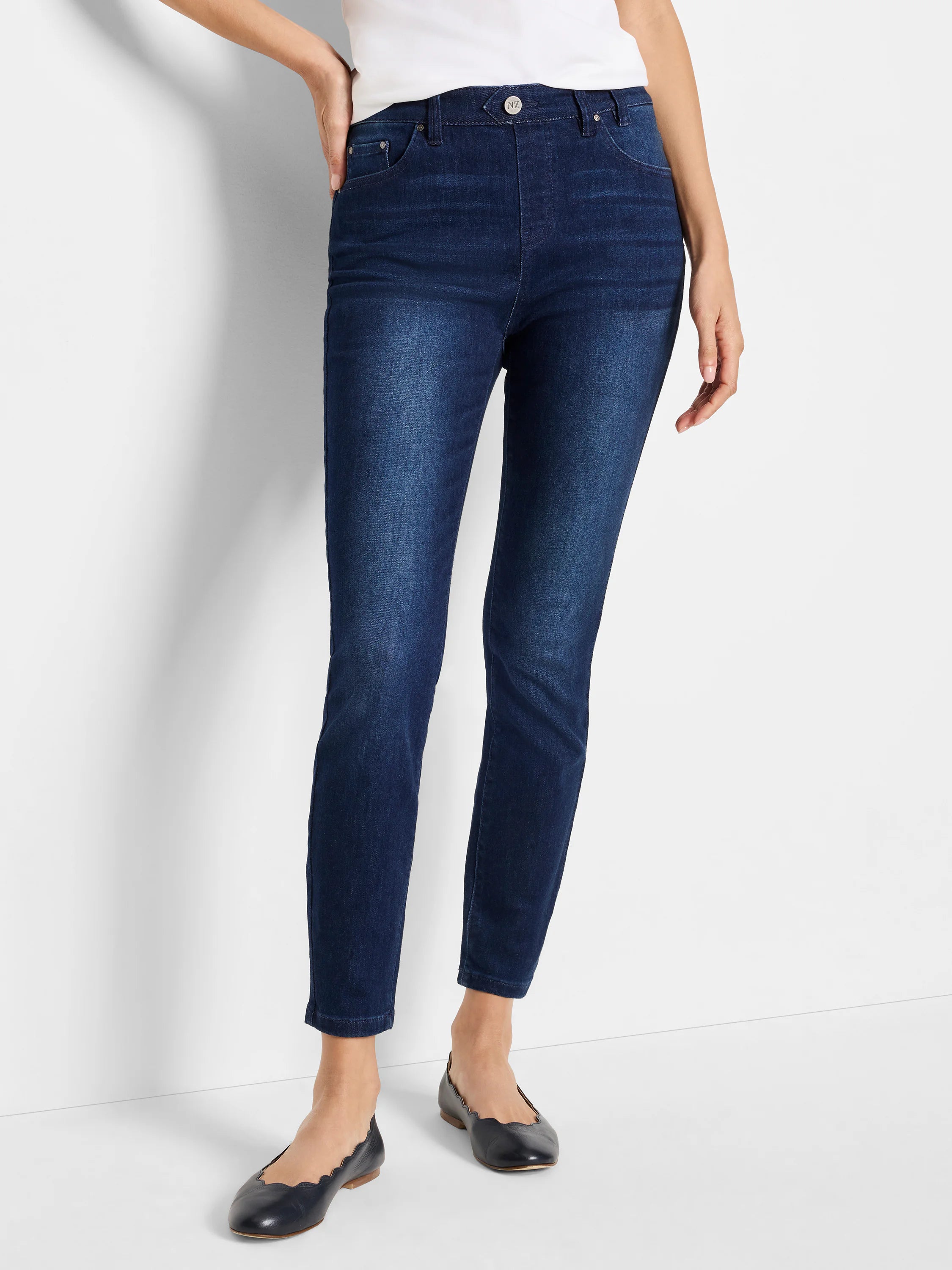 Dark wash, mid-rise slim ankle jeans on a model.  The jeans are a deep blue.