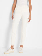 Off-white slim ankle jeans on a model, featuring a front button closure and pockets.