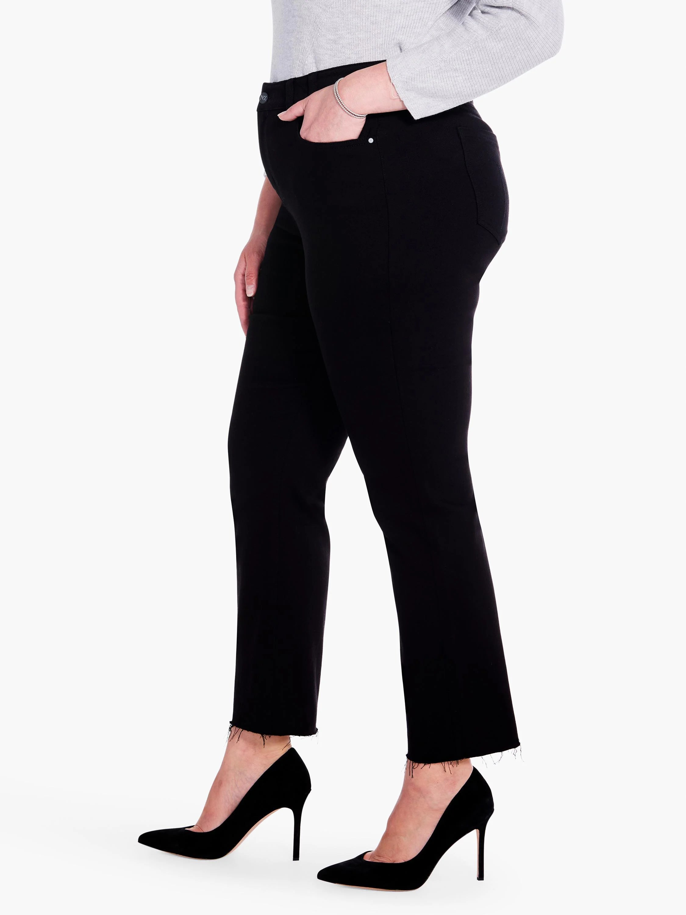 Black straight ankle jeans with a raw hem worn by a model, hand in pocket.