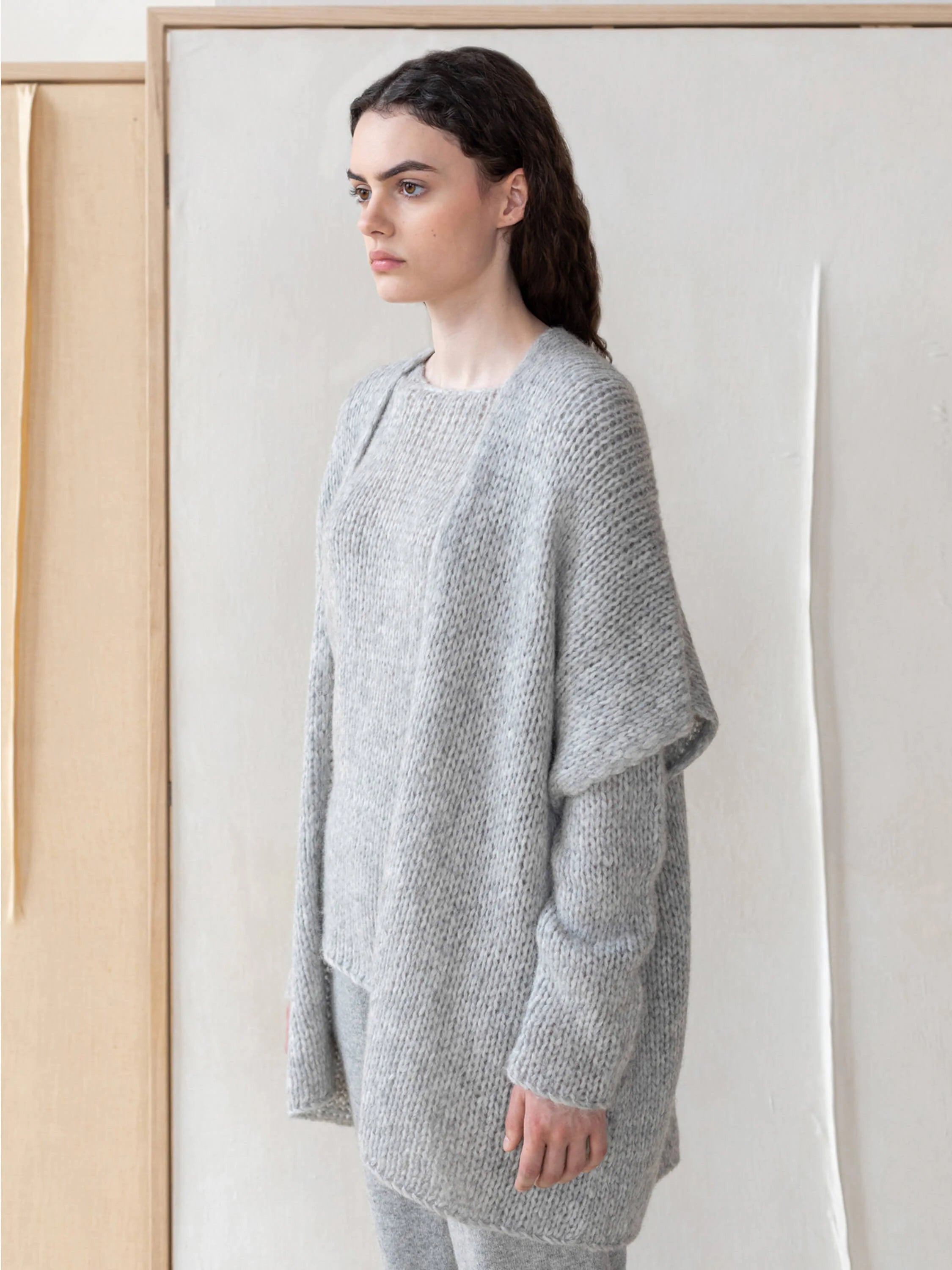 Light gray, loosely knit, oversized vest with dropped shoulders and asymmetrical hem.