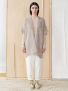 Beige knitted vest; open front, short sleeves.  Model wears it over a lighter beige top.