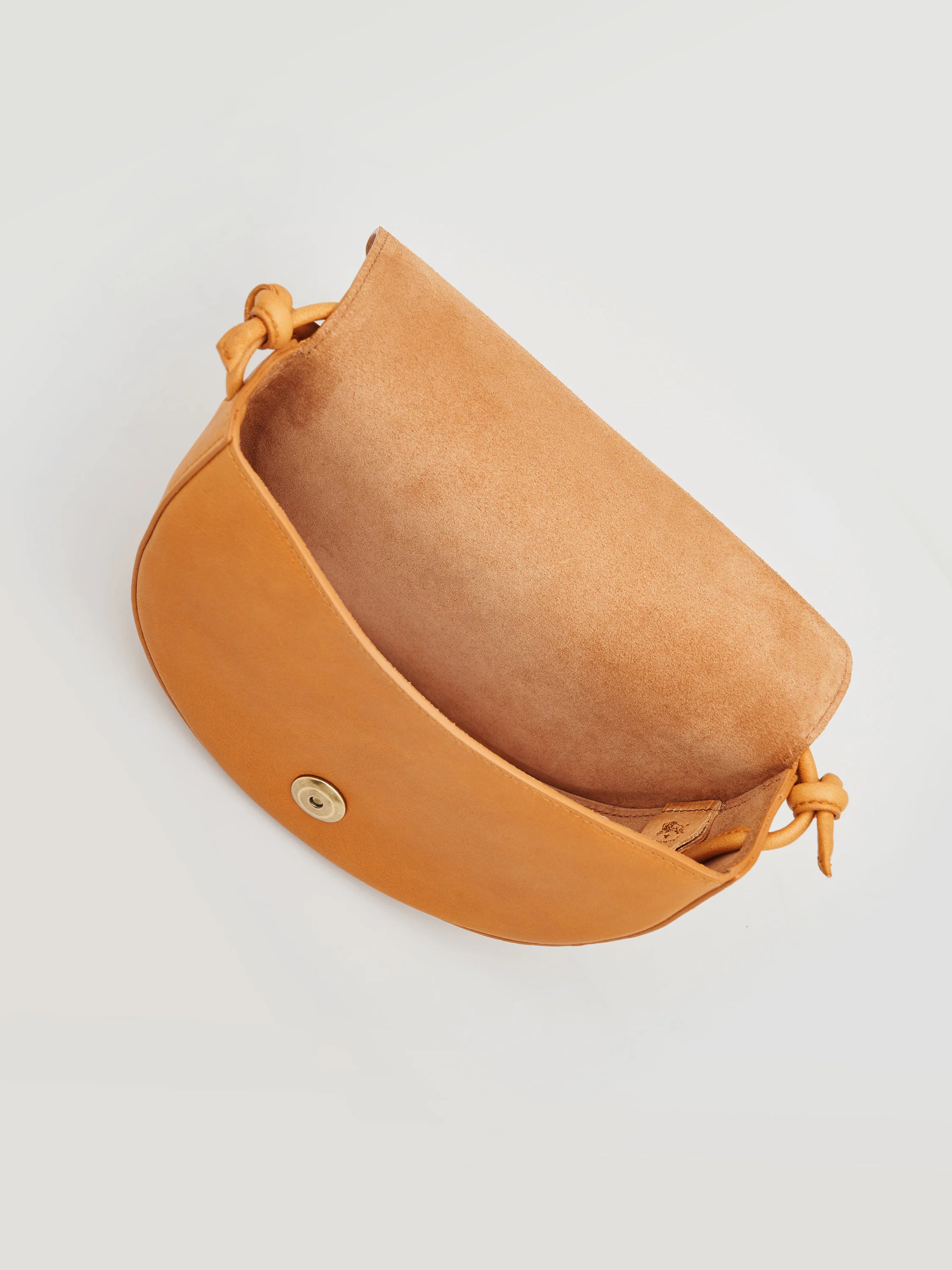 Small, half-moon shaped tan leather crossbody bag.  Light tan interior.  Brass button closure.  Knotted leather strap.