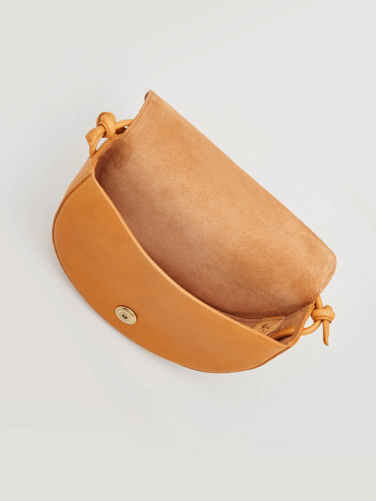 Small, half-moon shaped tan leather crossbody bag.  Light tan interior.  Brass button closure.  Knotted leather strap.