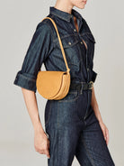 Small tan leather half-moon crossbody bag with a thin tan strap.