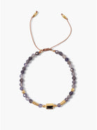 Purple and gold beaded bracelet with a central dark purple stone.  Brown cord closure.