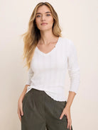 White pointelle rib long sleeve tee with V-neck and ruffled edges at neckline, cuffs, and hem.