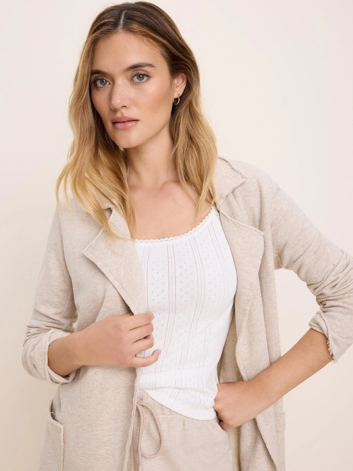 Heather oatmeal long French terry jacket with raw-edge lapels, cuffs, and pockets, worn open.