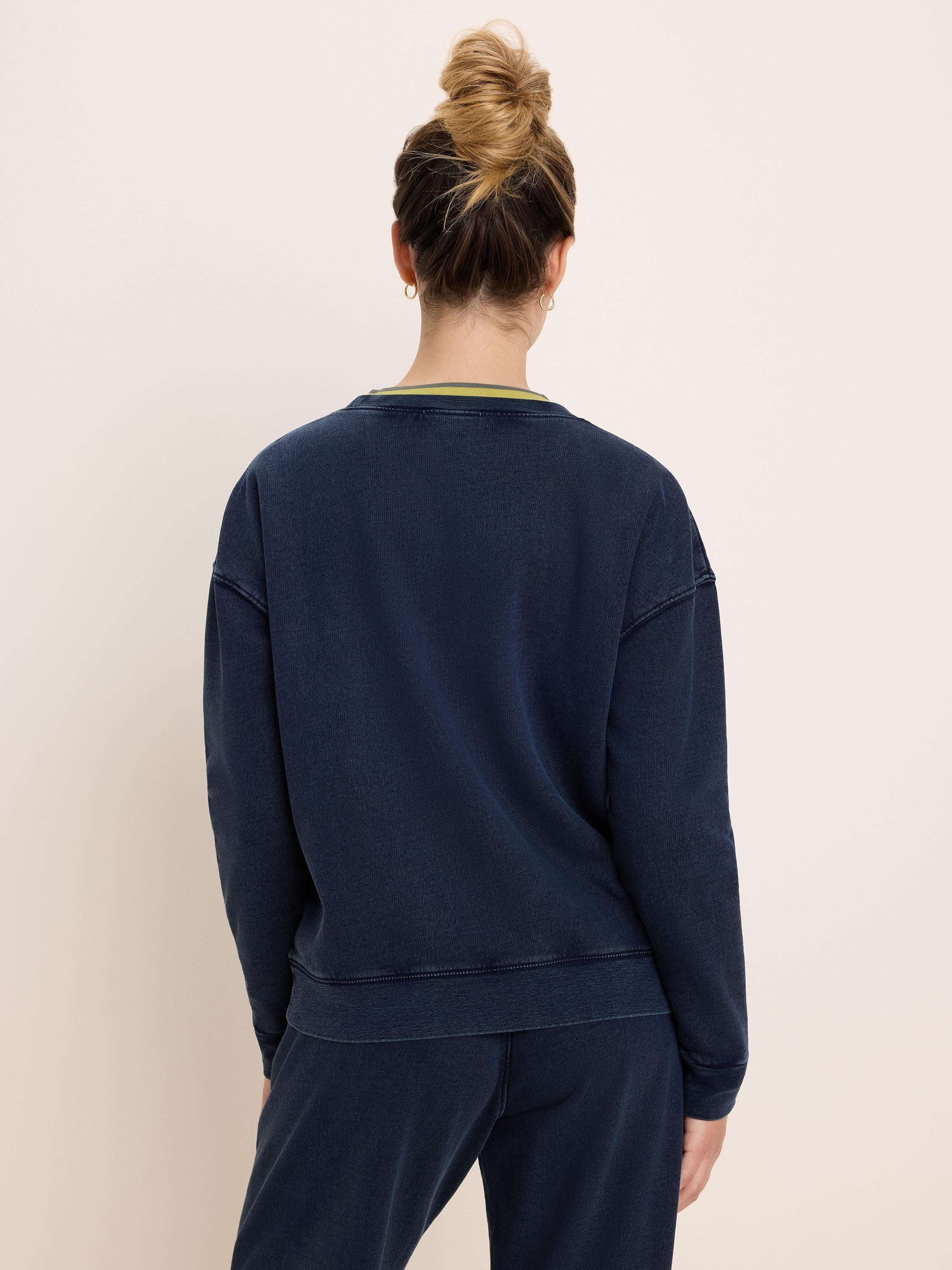 Washed navy cotton terry crewneck sweatshirt with visible stitching detail and a green stripe at the inner back collar.