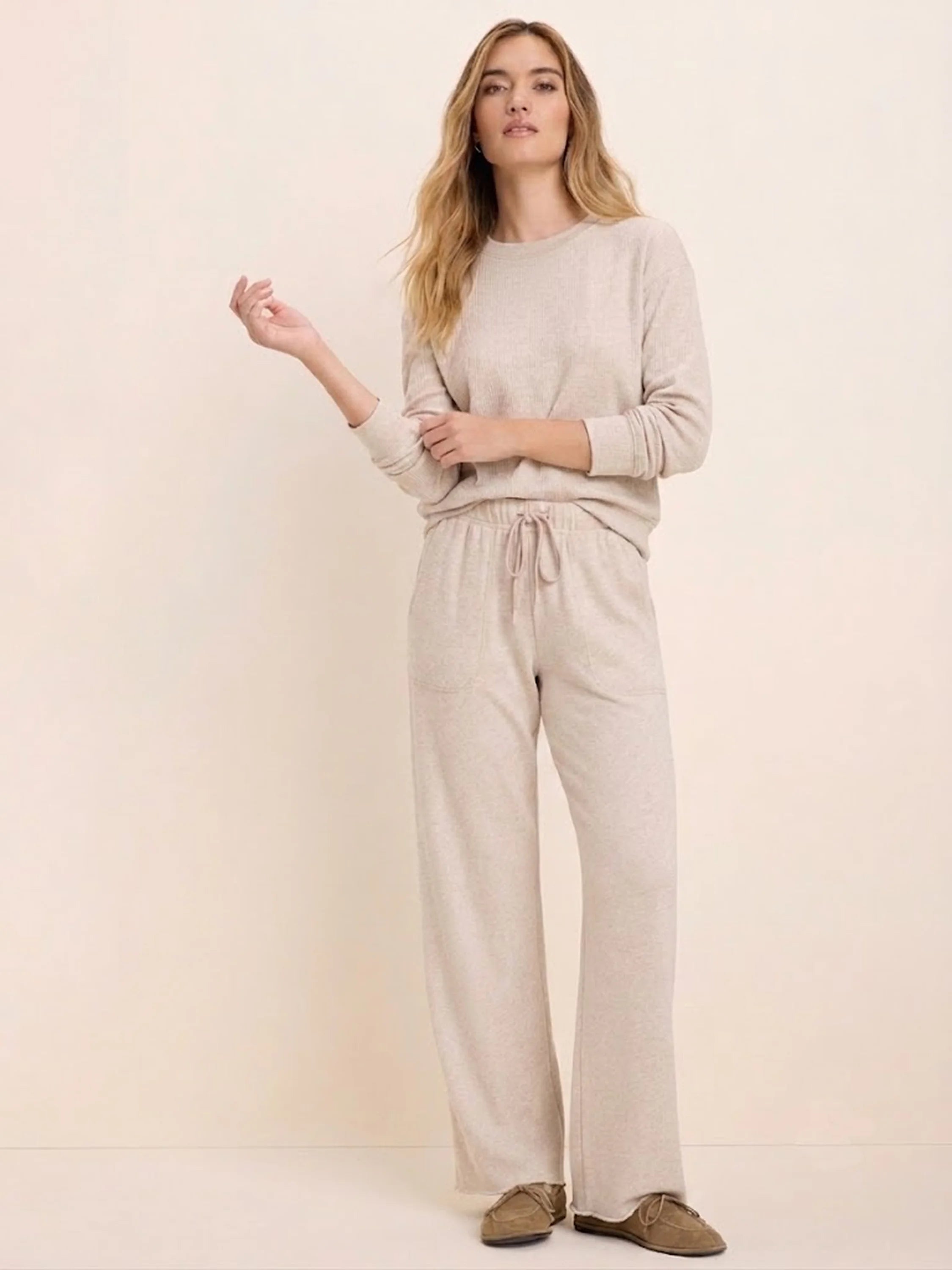 Model wears a light beige ribbed cotton terry crew neck top with long sleeves, paired with matching drawstring pants.
