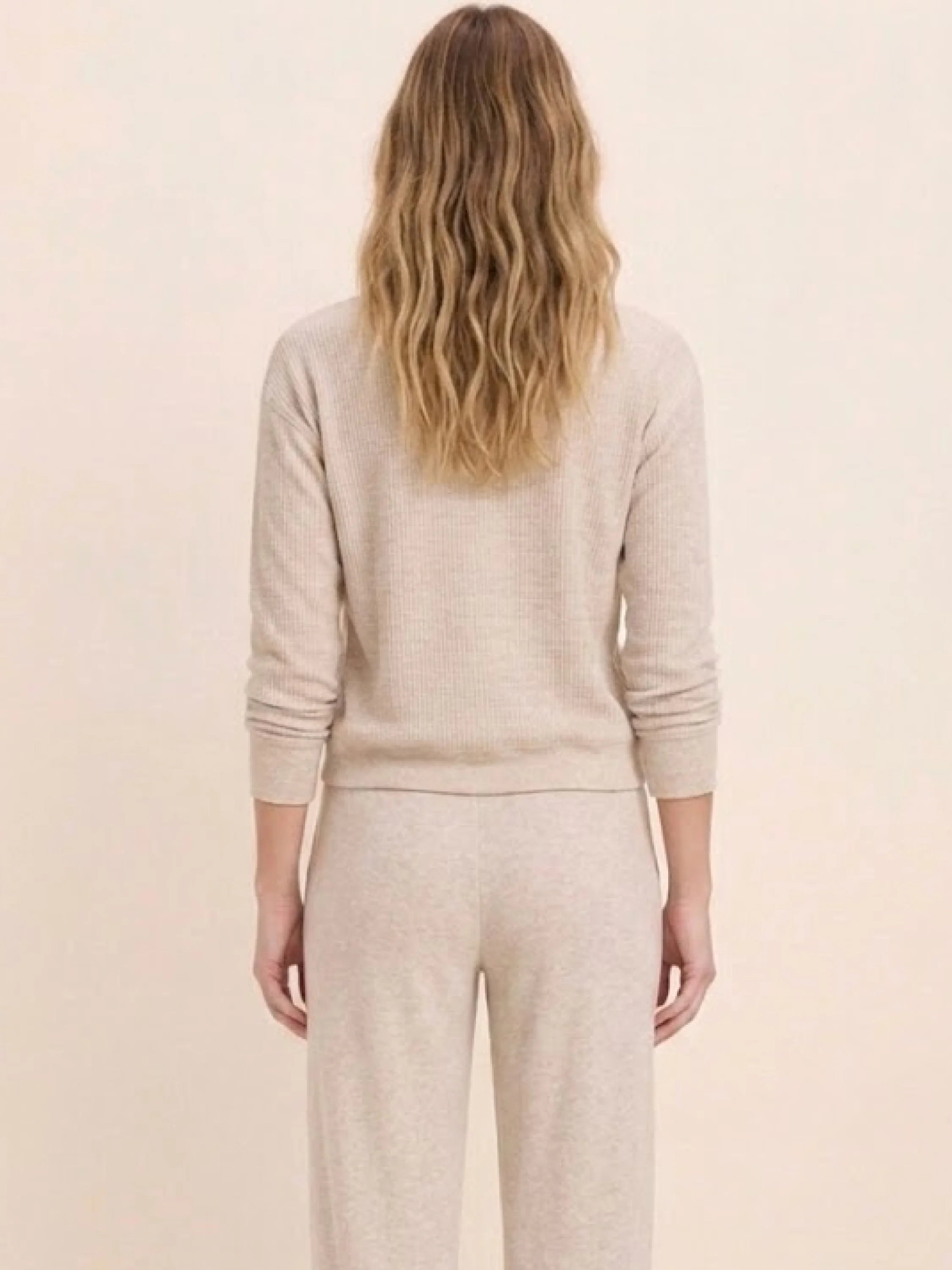 Back view of a model in a light beige, ribbed cotton terry crew neck long-sleeve top.