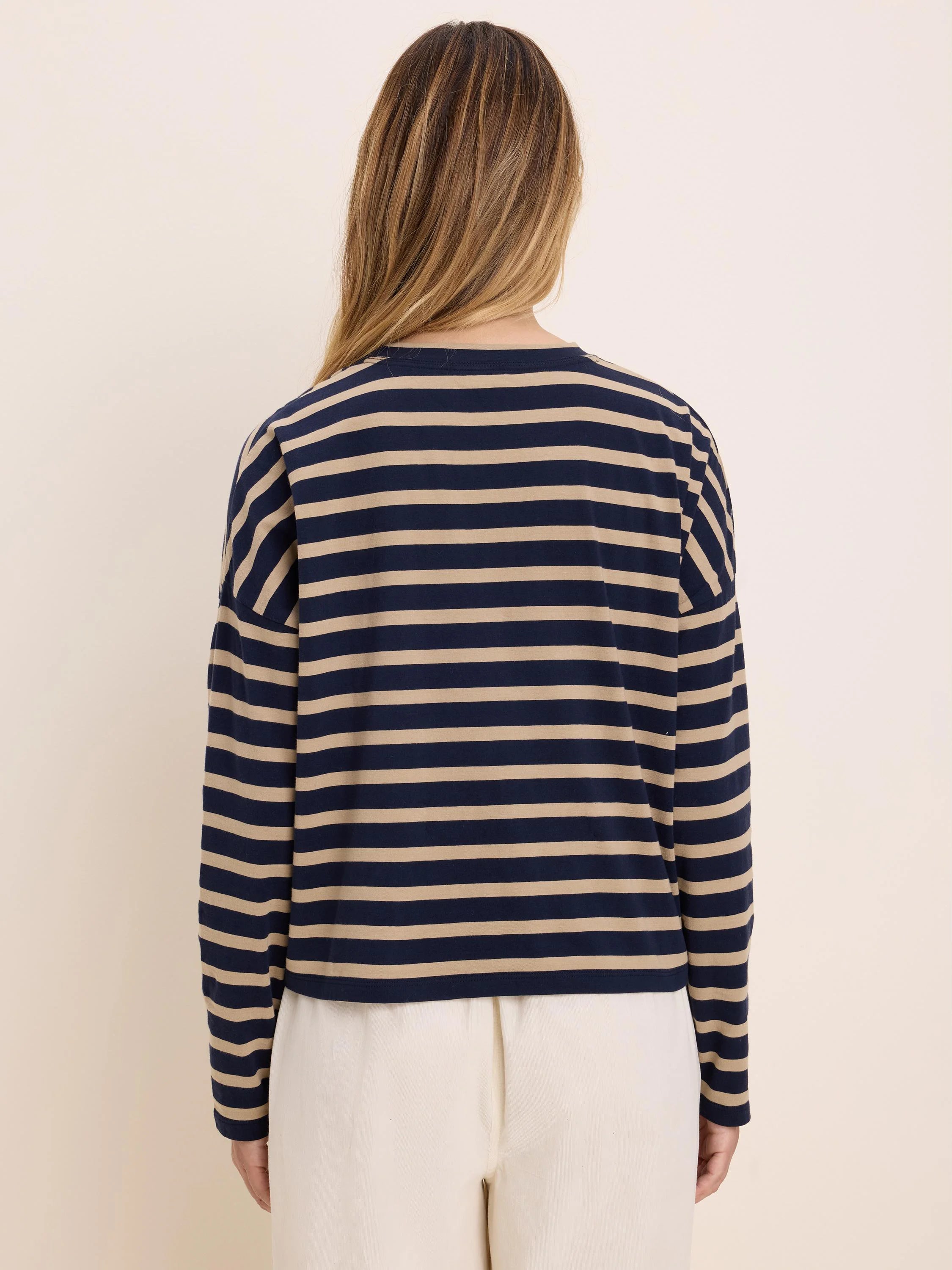 Long-sleeved tee with horizontal navy blue and beige stripes. Model from behind.