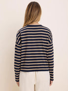 Long-sleeved tee with horizontal navy blue and beige stripes. Model from behind.