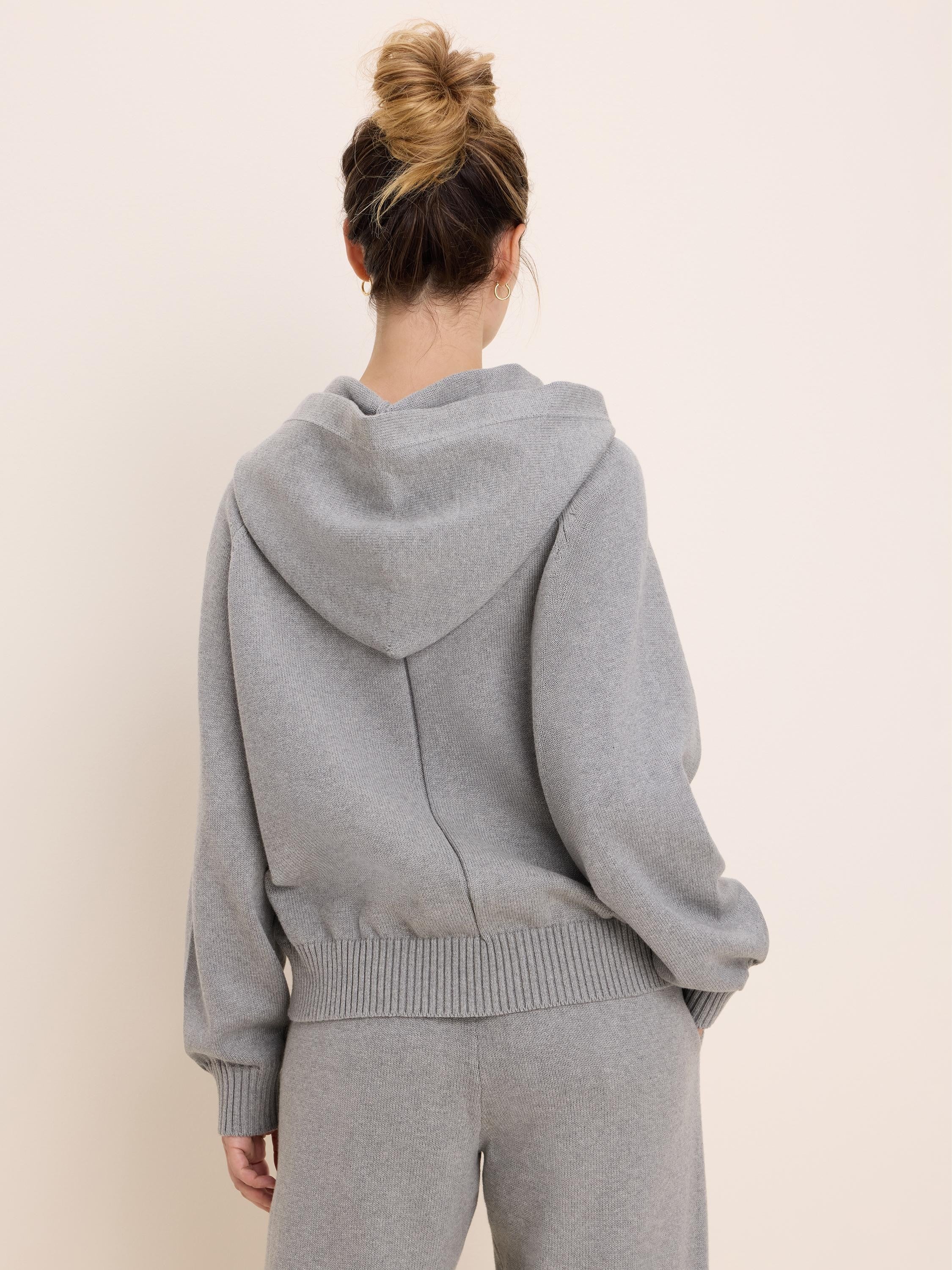 Light gray knit sweater hoodie, viewed from the back. Features a hood, ribbed cuffs, and a ribbed hem.