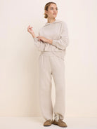 Loose-fit oatmeal knit sweater hoodie with an attached hood, long raglan sleeves, and ribbed cuffs and hem.