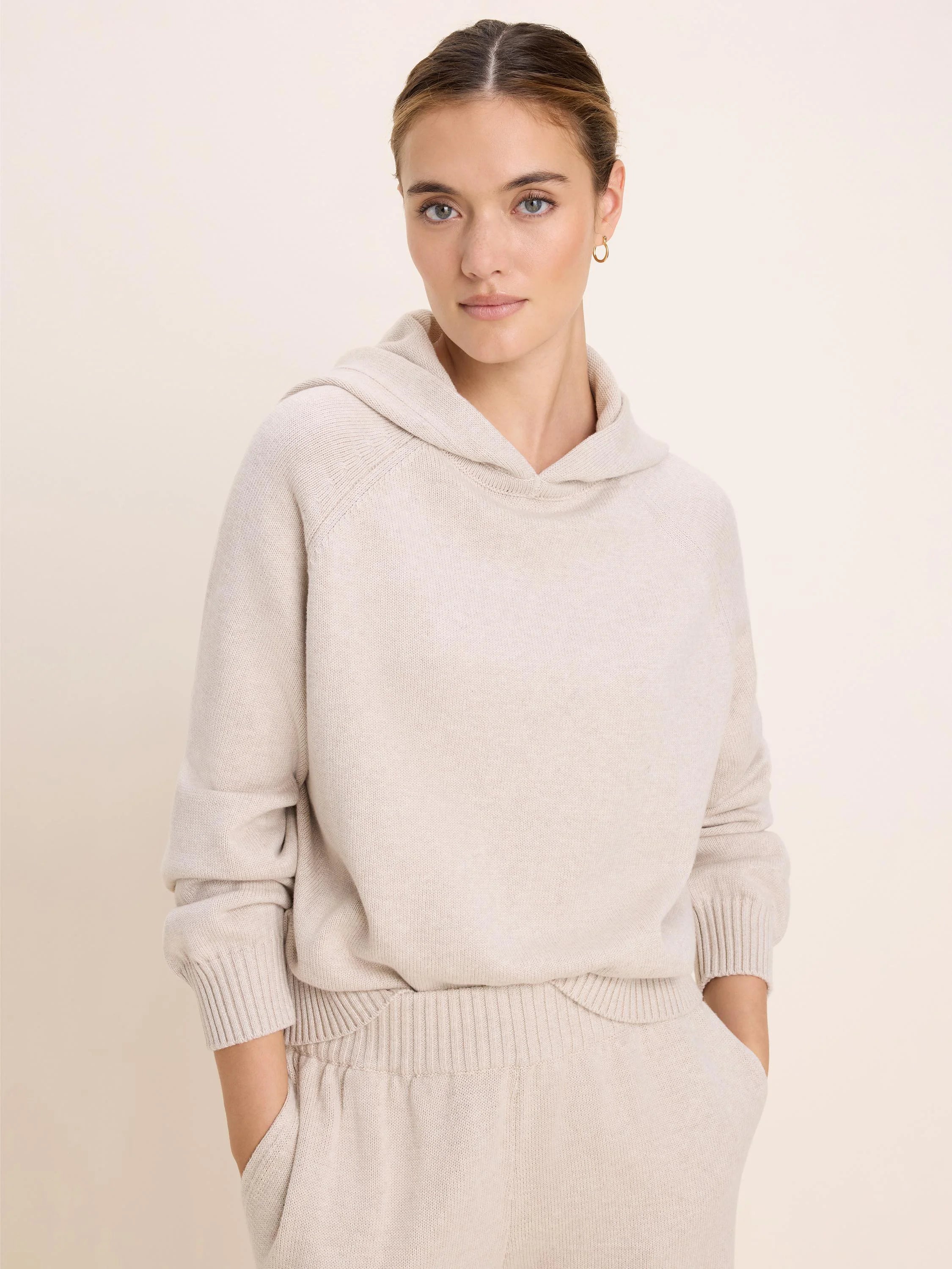 Light beige knit sweater hoodie with raglan sleeves, ribbed cuffs, and hem. Appears soft.