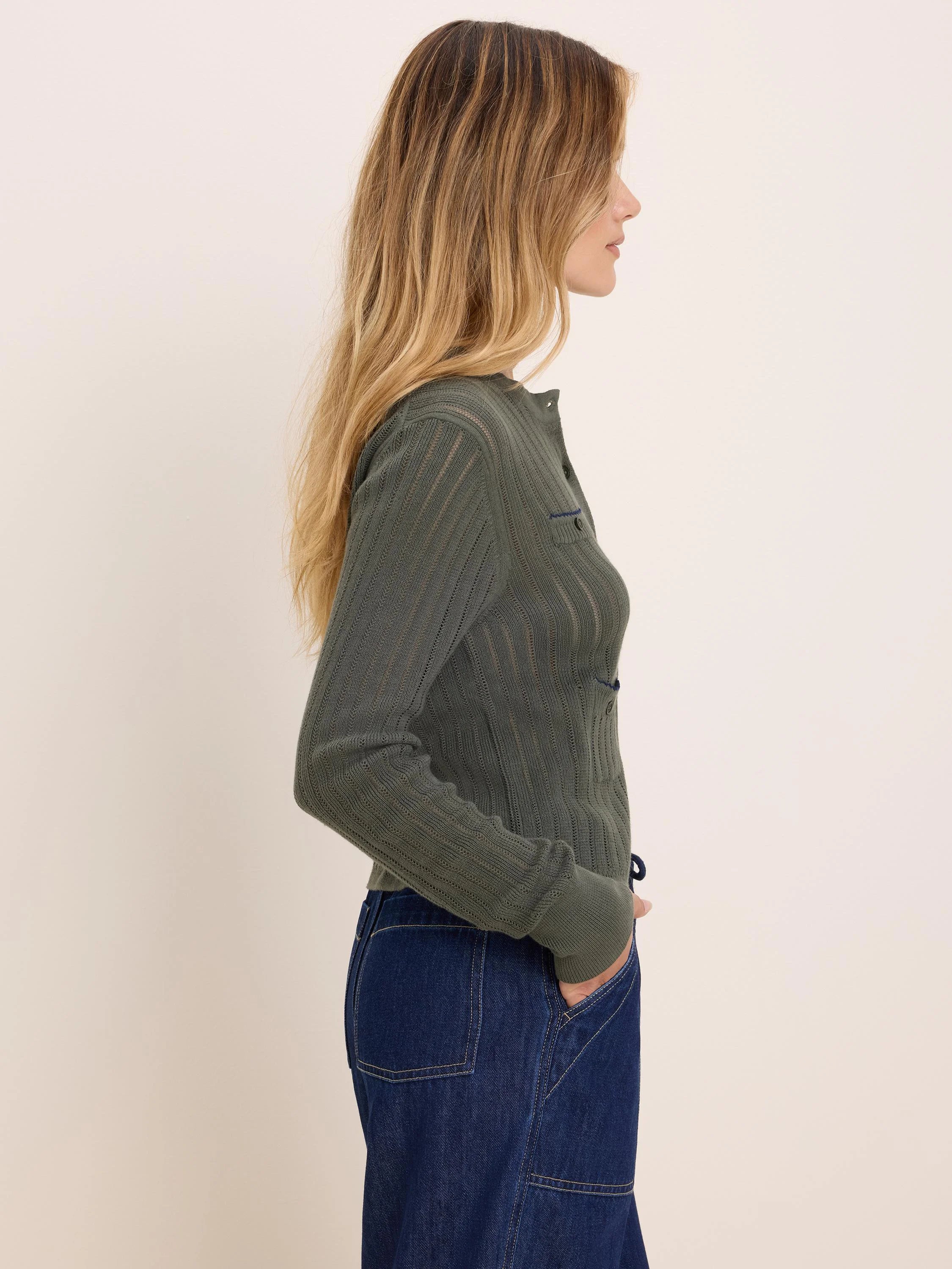 Olive green button-up cardigan with pointelle knit vertical stripes and a small chest pocket with blue trim.