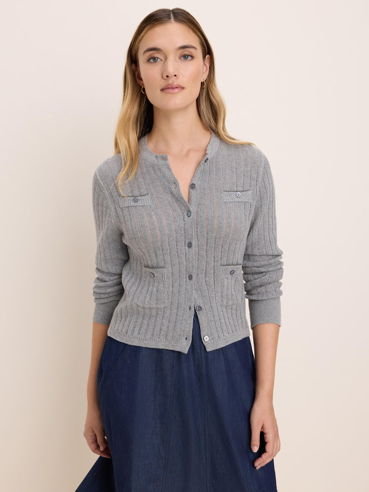 Light grey pointelle knit cardigan with visible holes, front buttons, and two buttoned chest pockets.