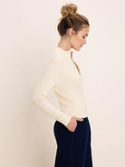 Cream ribbed half-zip sweater with a gold zipper partially open, mock neck.