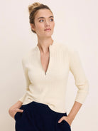 Off-white ribbed half-zip sweater with a stand-up collar and silver zipper.