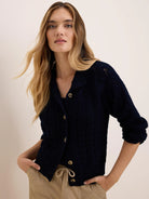 Navy blue cable knit cardigan with a collar, light brown buttons, and 3/4 sleeves with gathered cuffs.