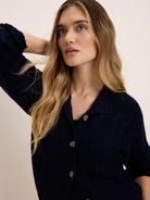 Dark navy cable knit cardigan featuring a collar and light-colored buttons.