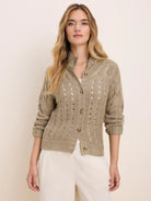 Taupe cable knit cardigan with openwork details, ribbed collar & cuffs, and brown buttons down the front.