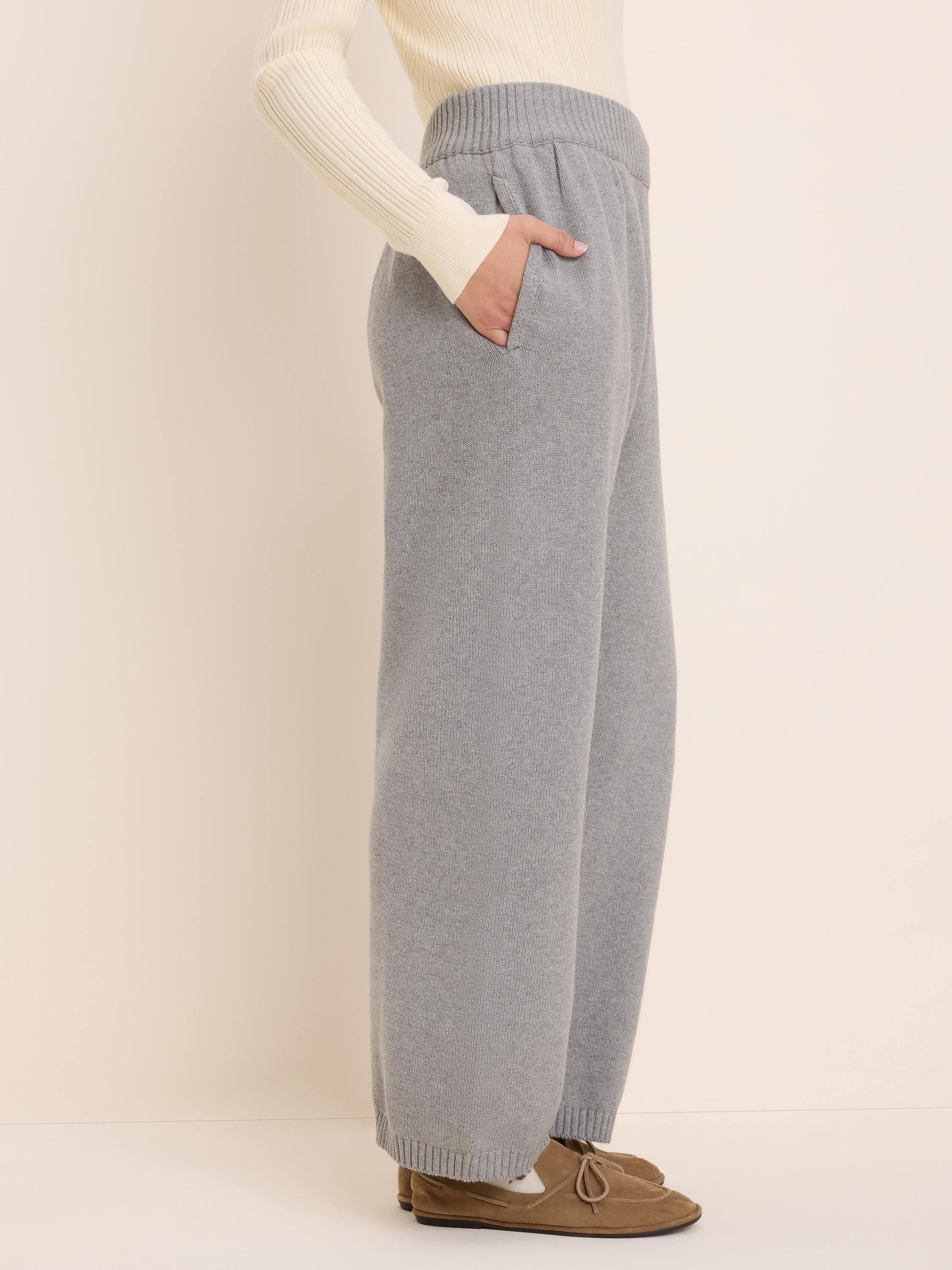 Light grey knit sweater pants with a ribbed elastic waist, side pockets, and wide legs with ribbed cuffs.