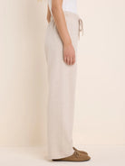 Heathered light beige wide-leg pant with a drawstring elastic waist and raw hem, worn from waist to feet.