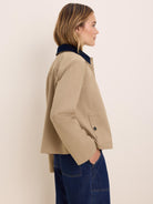 Tan twill jacket with a navy corduroy collar. Casual cut, features a buttoned patch pocket.