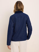 Back view of a dark blue denim trucker jacket. It features a visible back yoke and a contrasting dark navy collar.