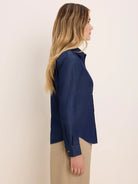 Model wears a soft dark blue denim shirt. Collared, long sleeves with silver snap buttons.